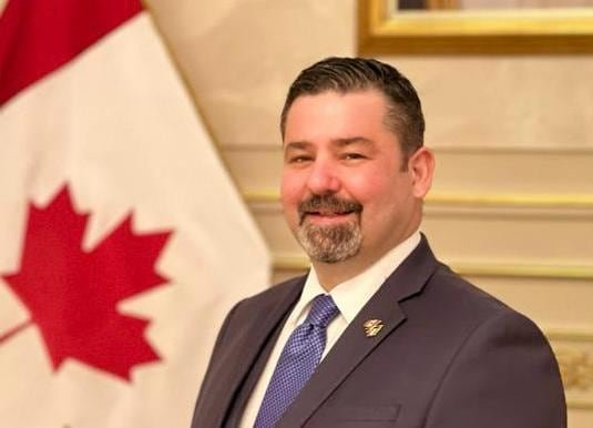 Tariq Gordon stands screen right, facing the camera and smiling.