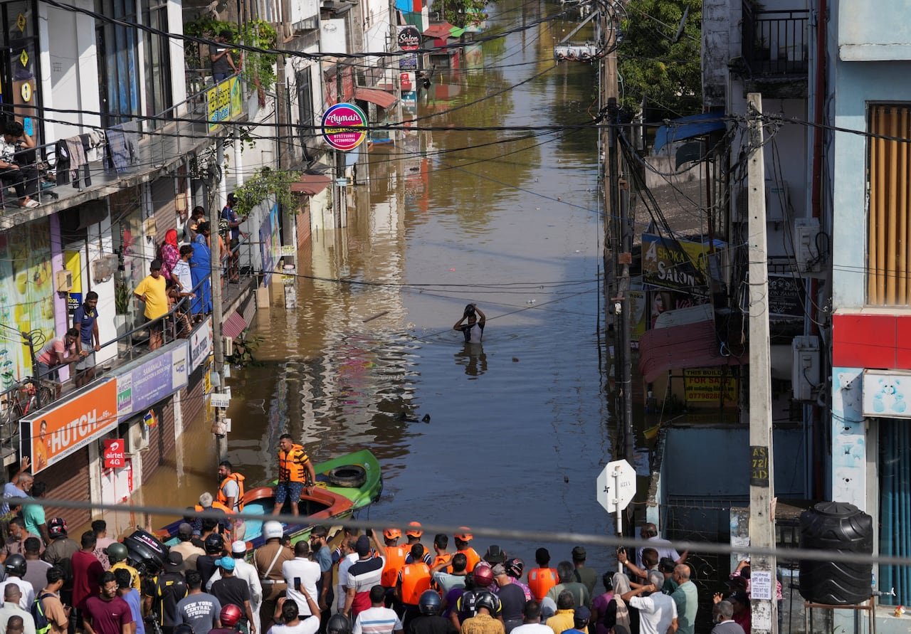 default-81 A man wades through a flooded street as people watch from buildings