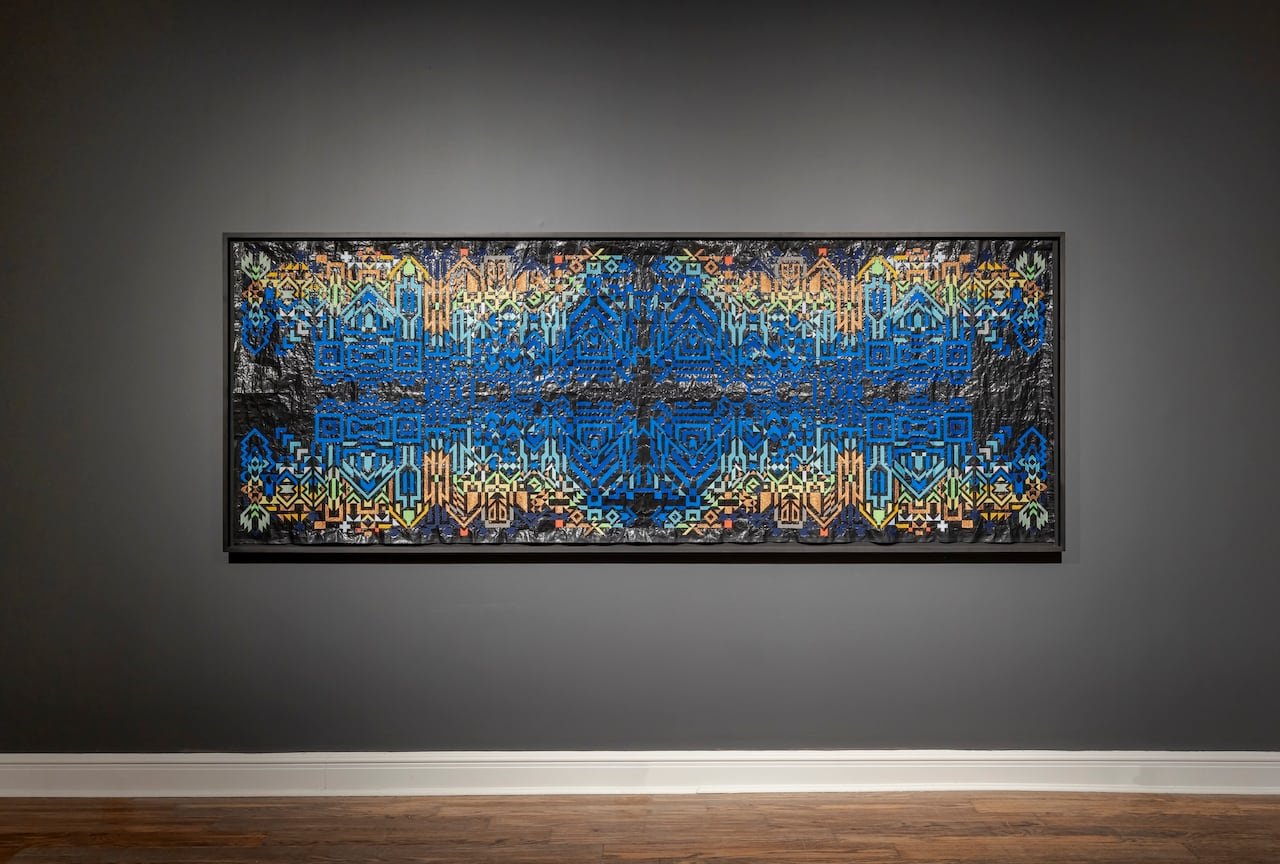 A large blue and gold embroidery hanging on a gallery wall.