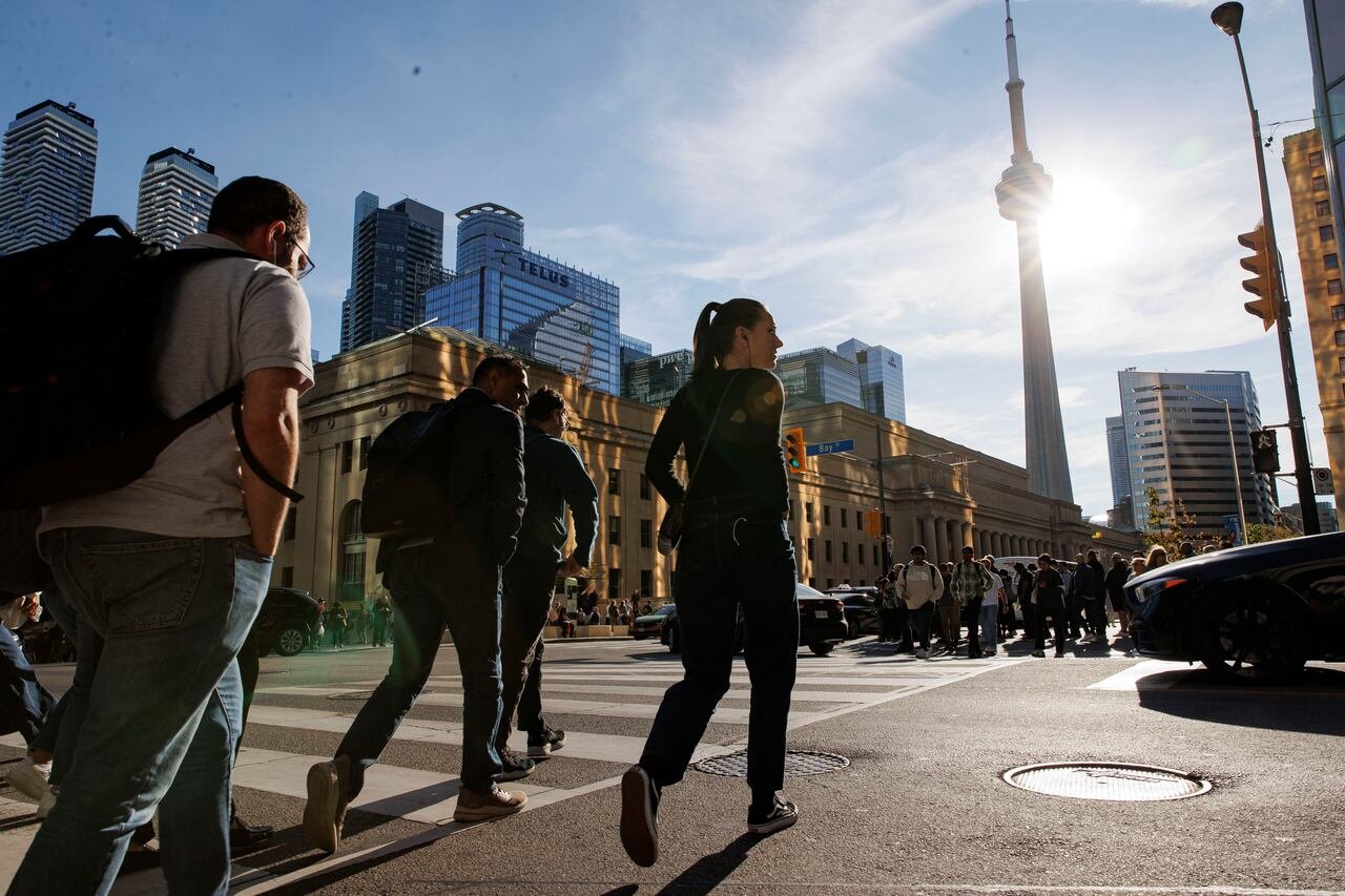 People walk across a crosswalk near Union Station in Toronto.