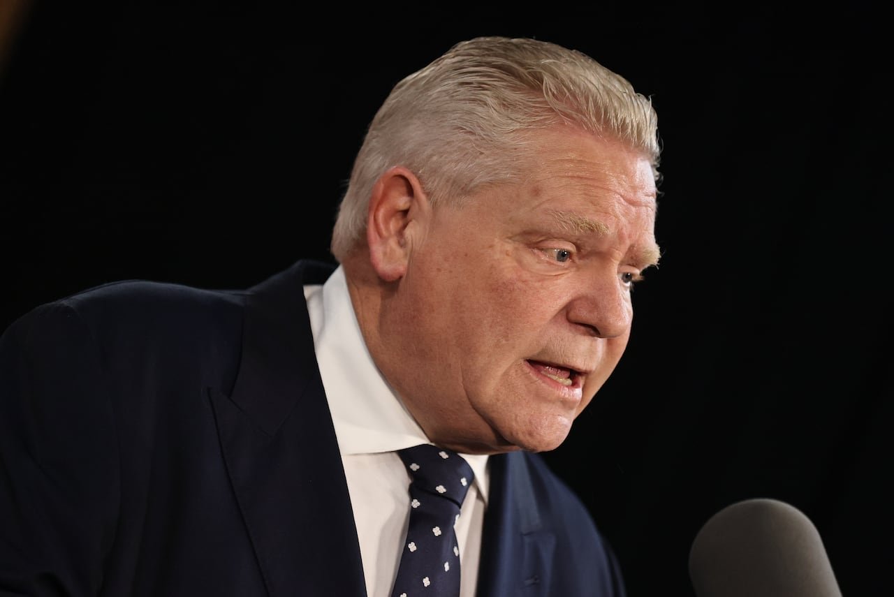 A man with blonde hair in a suit speaks.