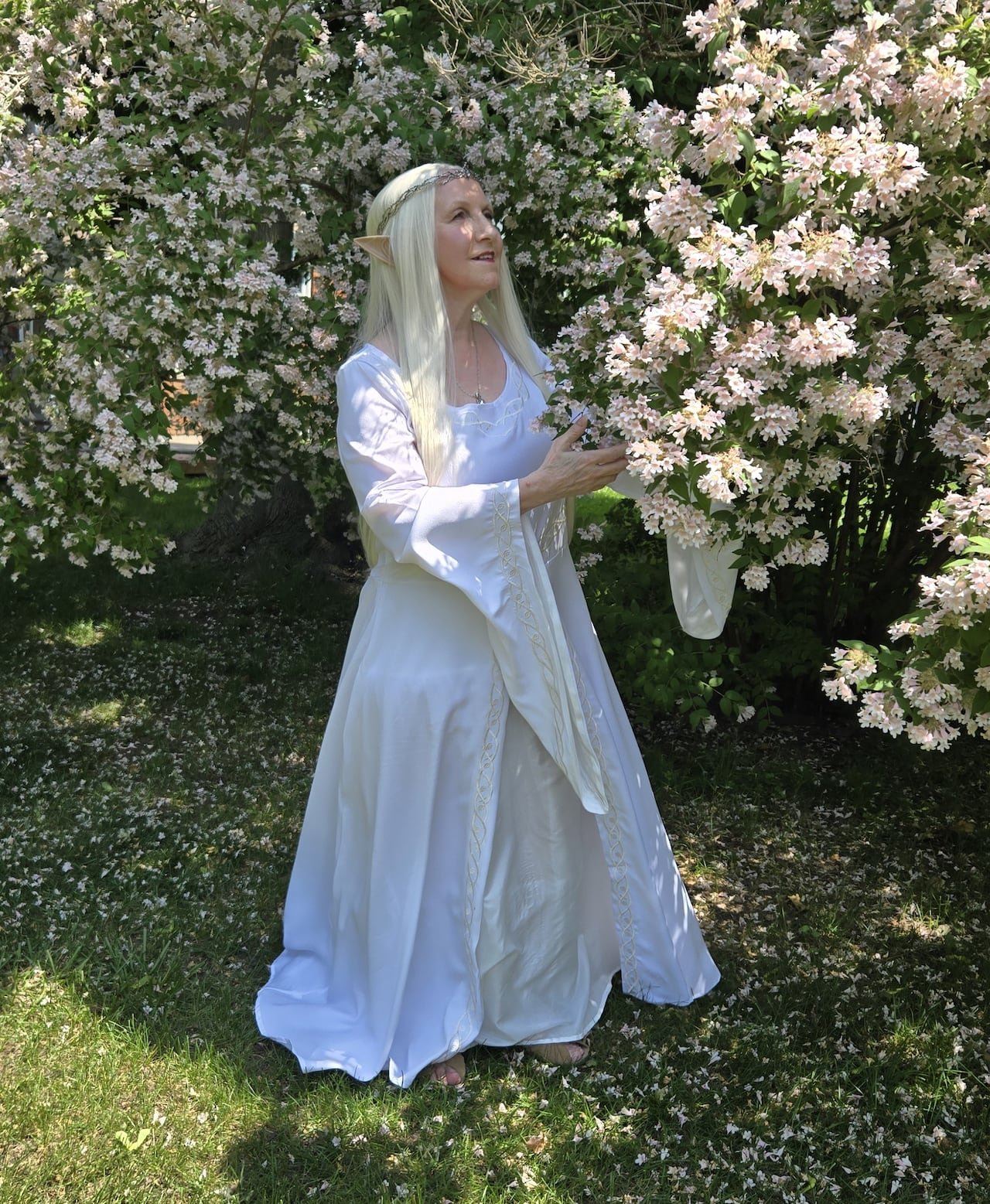 A woman is dressed in a white dress with a long blonde wig and pointed ears