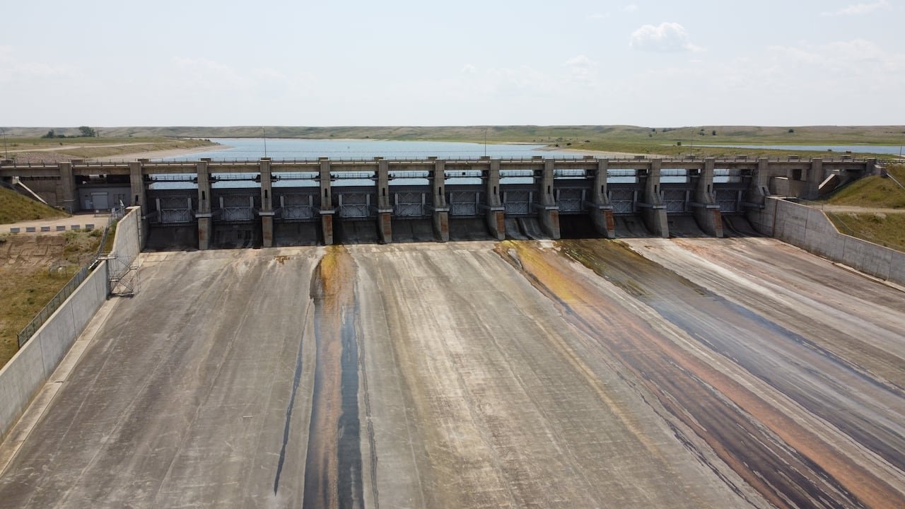 default-75 A large concrete structure sits in front of a large lake with vegetation on the side.