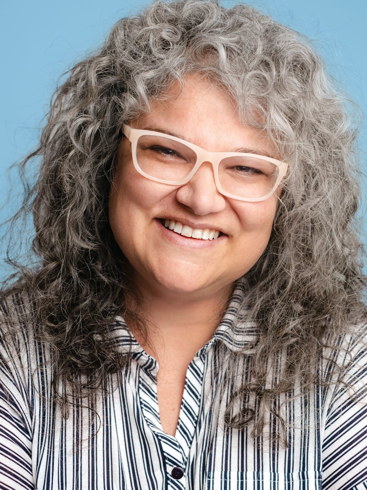 default-208 A woman wearing a striped shirt and glasses is shown in close-up.